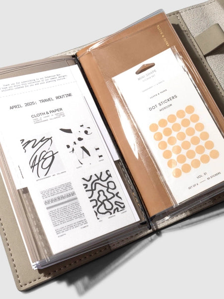 Open notebook with printed pages and a sheet of dot stickers on a white background