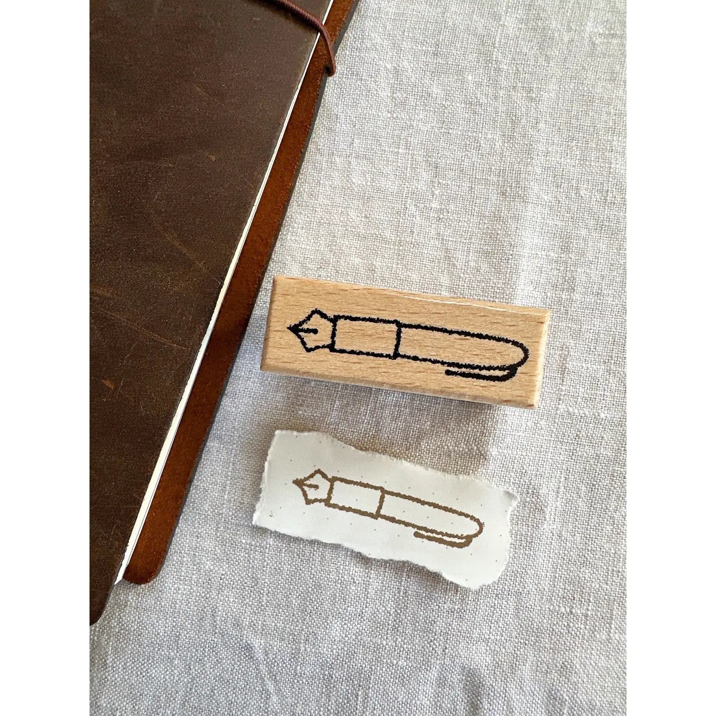 Wooden stamp with a pen design on a textured fabric surface