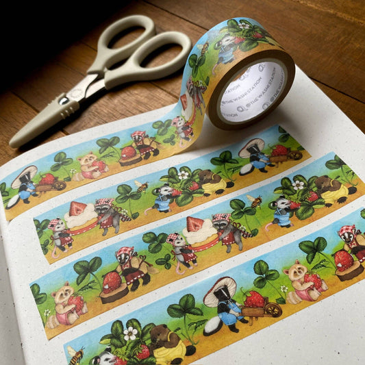 Decorative tape with cartoon raccoons and scissors on a wooden surface