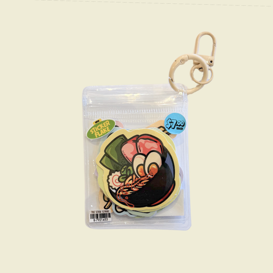 A packaged food-themed keychain or bag charm featuring a cartoon ramen illustration, sealed in a clear plastic zip bag with a beige metal clasp on a plain light background.