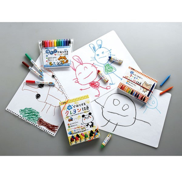 Coloring books and crayons with children's drawings on a gray surface