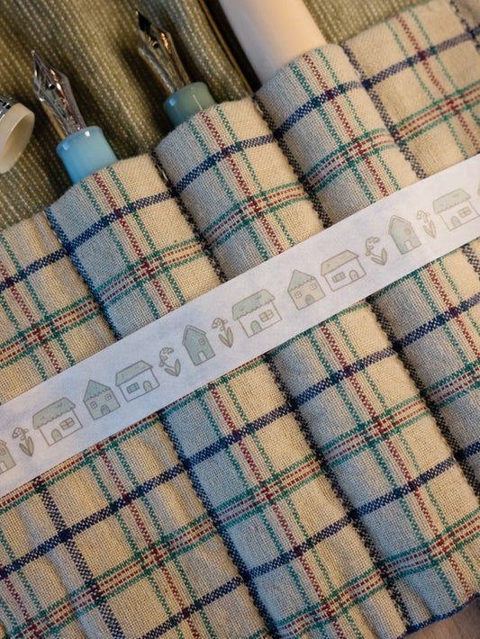 Plaid fabric with a ruler displaying house patterns and sewing tools.