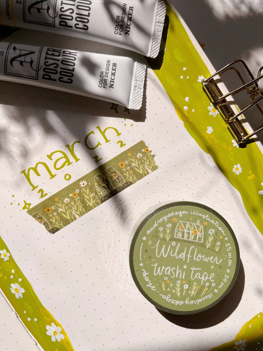 Container of Wildflower washi tape on a surface with 'March 2' text and stationery items.