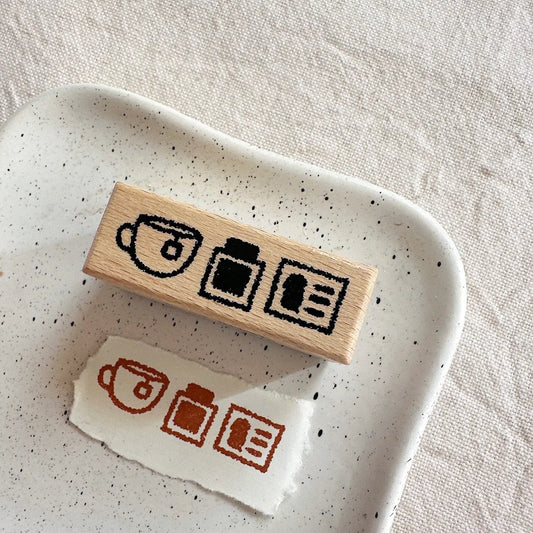Wooden stamp with coffee-themed designs on a speckled ceramic dish.