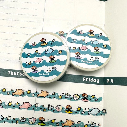 Two round washi tape rolls with cartoon designs on a notebook page.