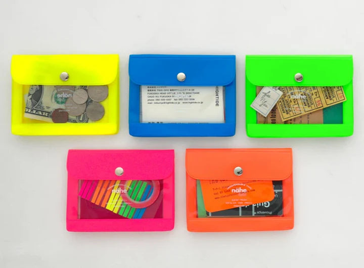 Five small rectangular card holder pouches in neon yellow, blue, green, pink, and orange, arranged in two rows on a white background. Each pouch has a snap button closure and a clear front window showing stored items like cash, an ID card, and tickets.