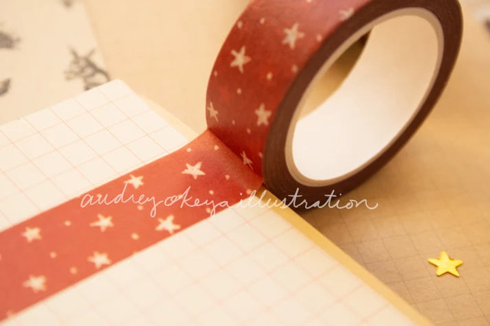 Roll of red washi tape with star patterns on a beige background