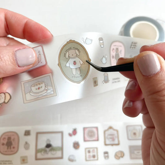 Hand applying decorative stickers to a surface with a small tool.