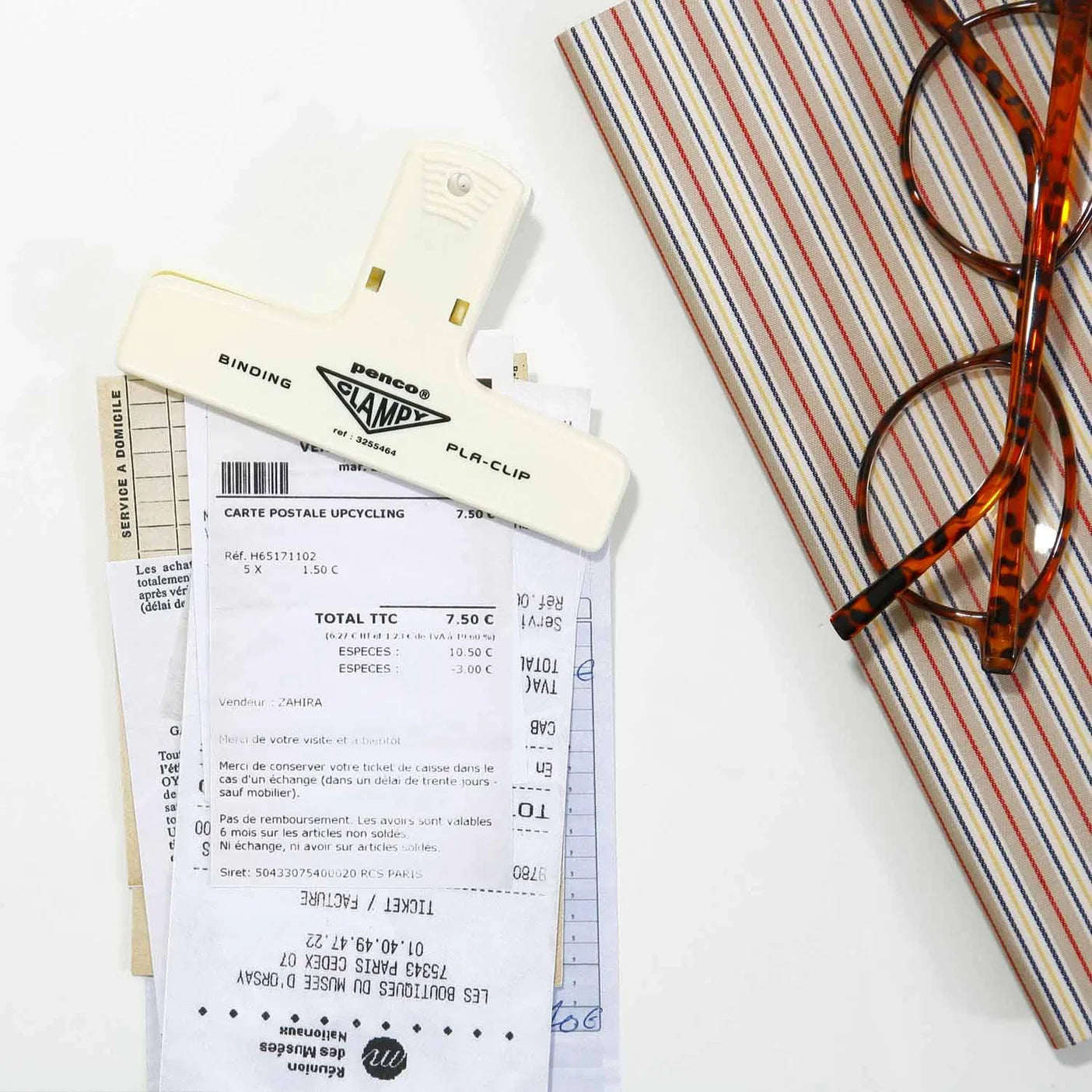 penco ivory clip holding a stack of papers and a notebook with pair of glasses on top