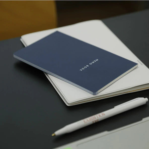 Blue notebook and white pen on a dark surface