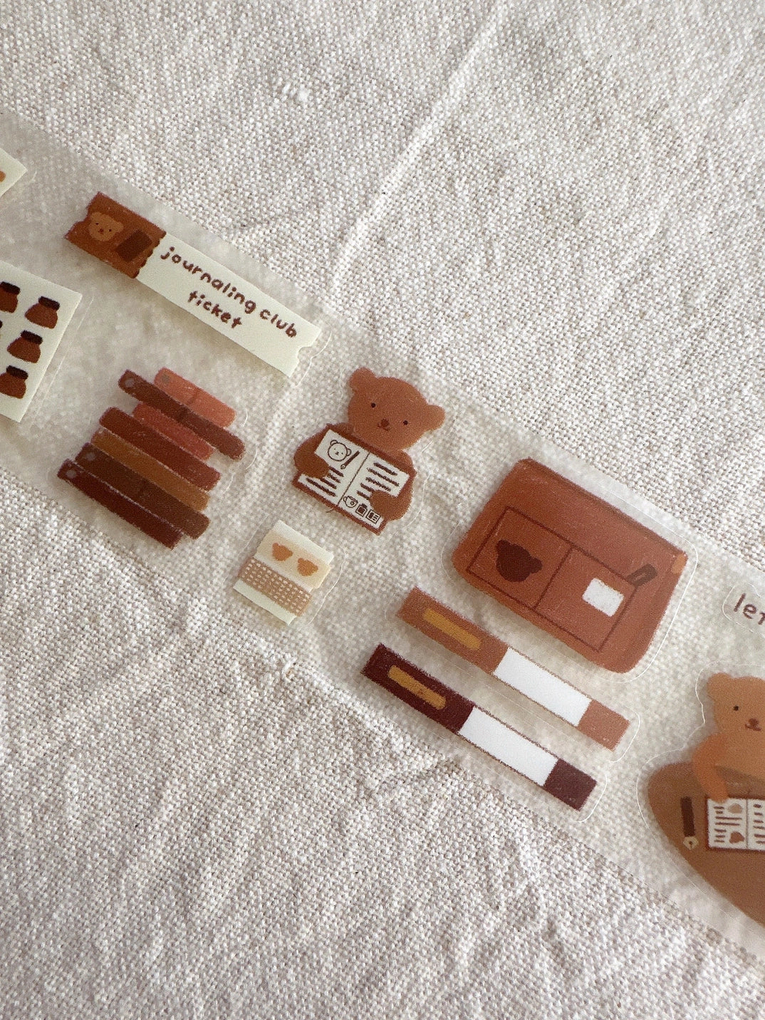 Set of small bear-themed stationery items on a textured surface