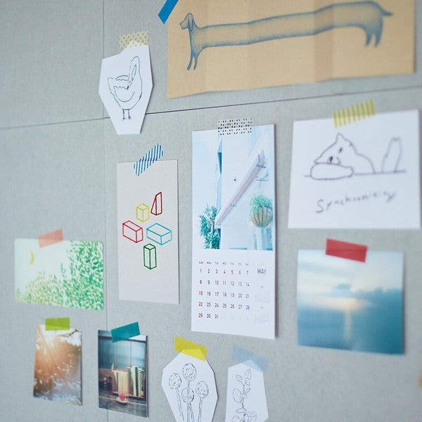 Collection of small prints and a calendar attached to a gray wall.