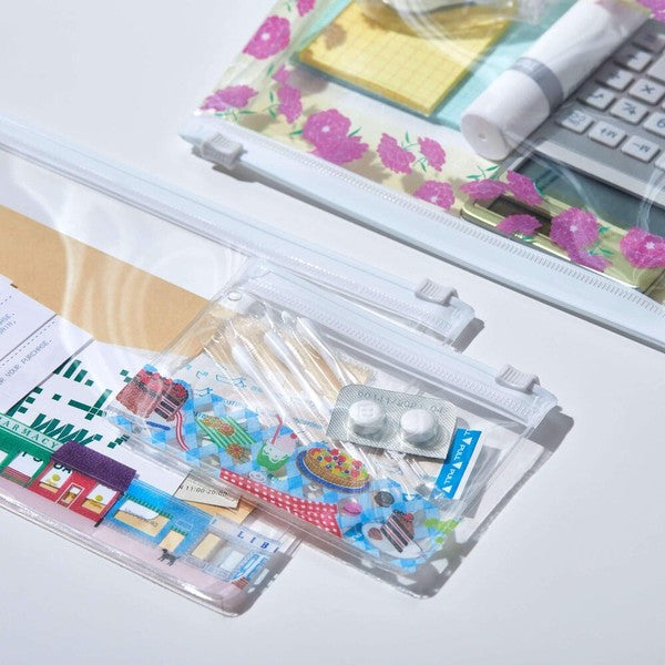 Set of stationery items including rulers and erasers in a clear case on a desk.