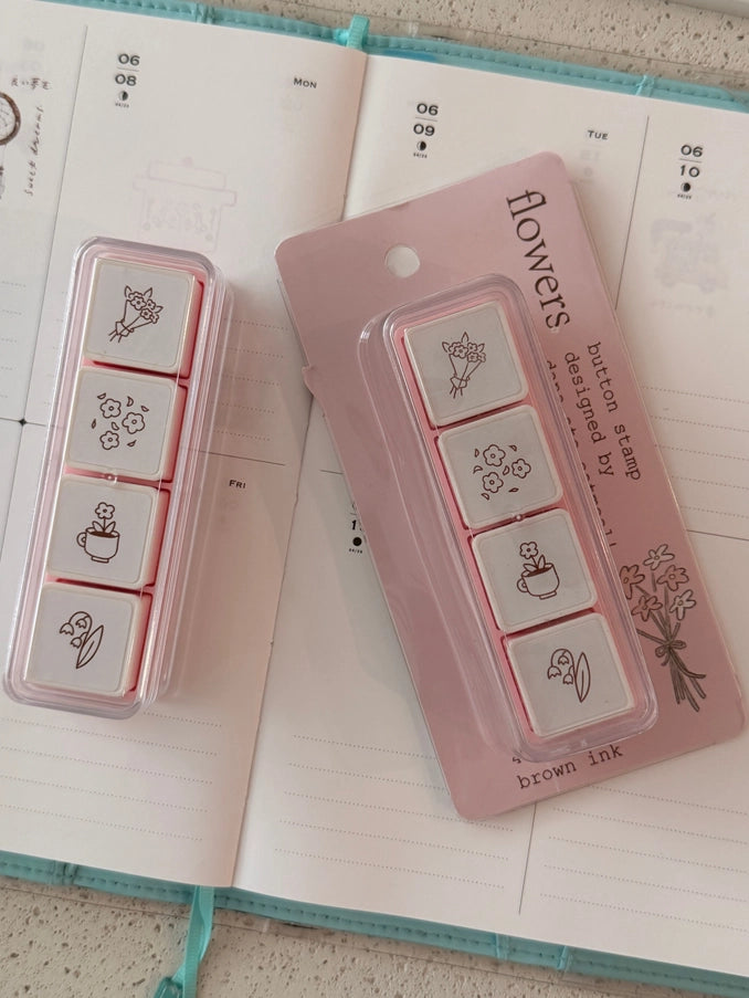 Set of rubber stamps with floral designs on a pink card, placed on an open notebook.
