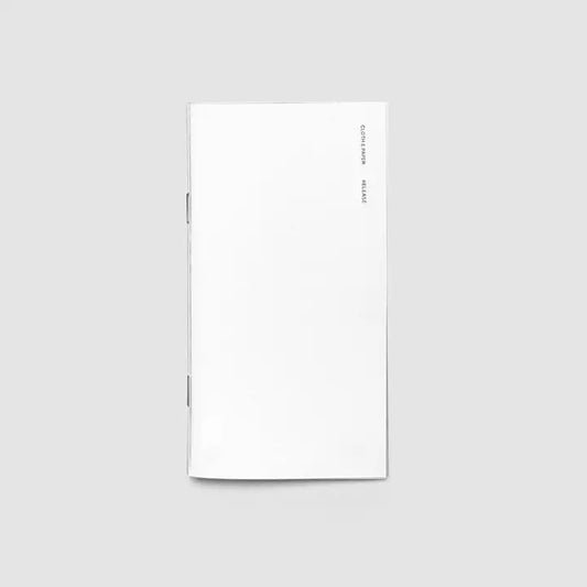 A minimalist white notebook or journal with a clean, blank cover, shown vertically against a solid light gray background.