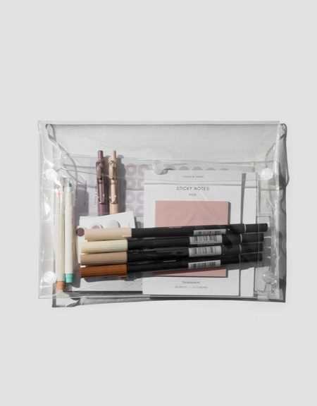 Clear plastic pouch containing stationery items on a white background