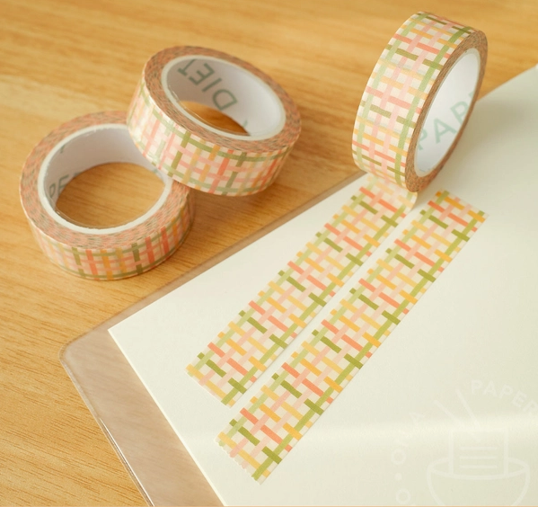 Three rolls of decorative tape with patterned designs on a wooden surface.