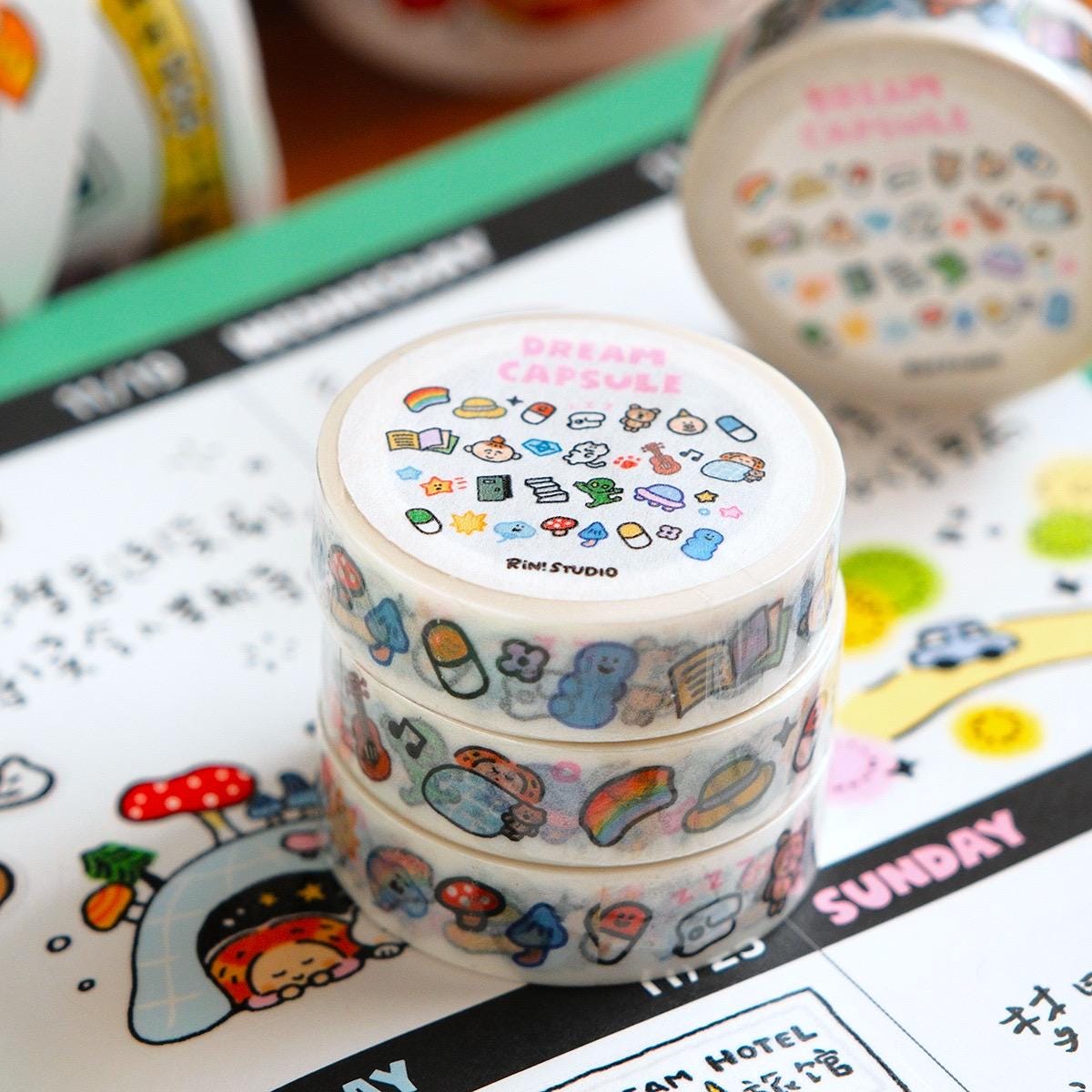Three rolls of decorative tape with cartoon designs on a planner page.