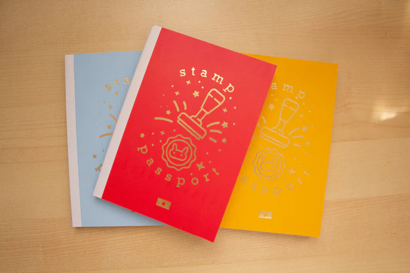Three colorful notebooks with stamp designs on a wooden surface
