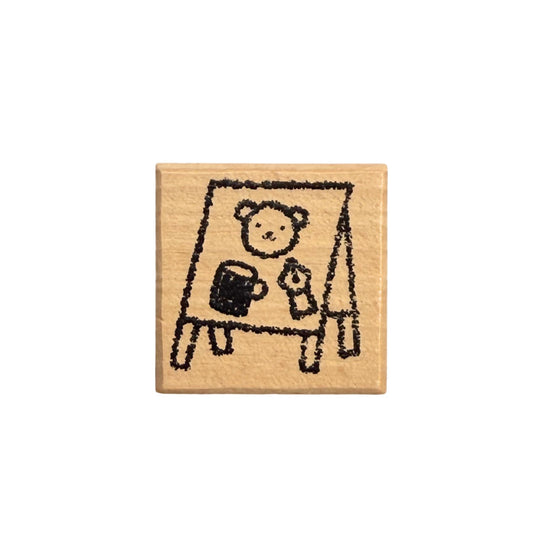Wooden stamp with a cartoon bear holding a mug and a teddy bear on a white background