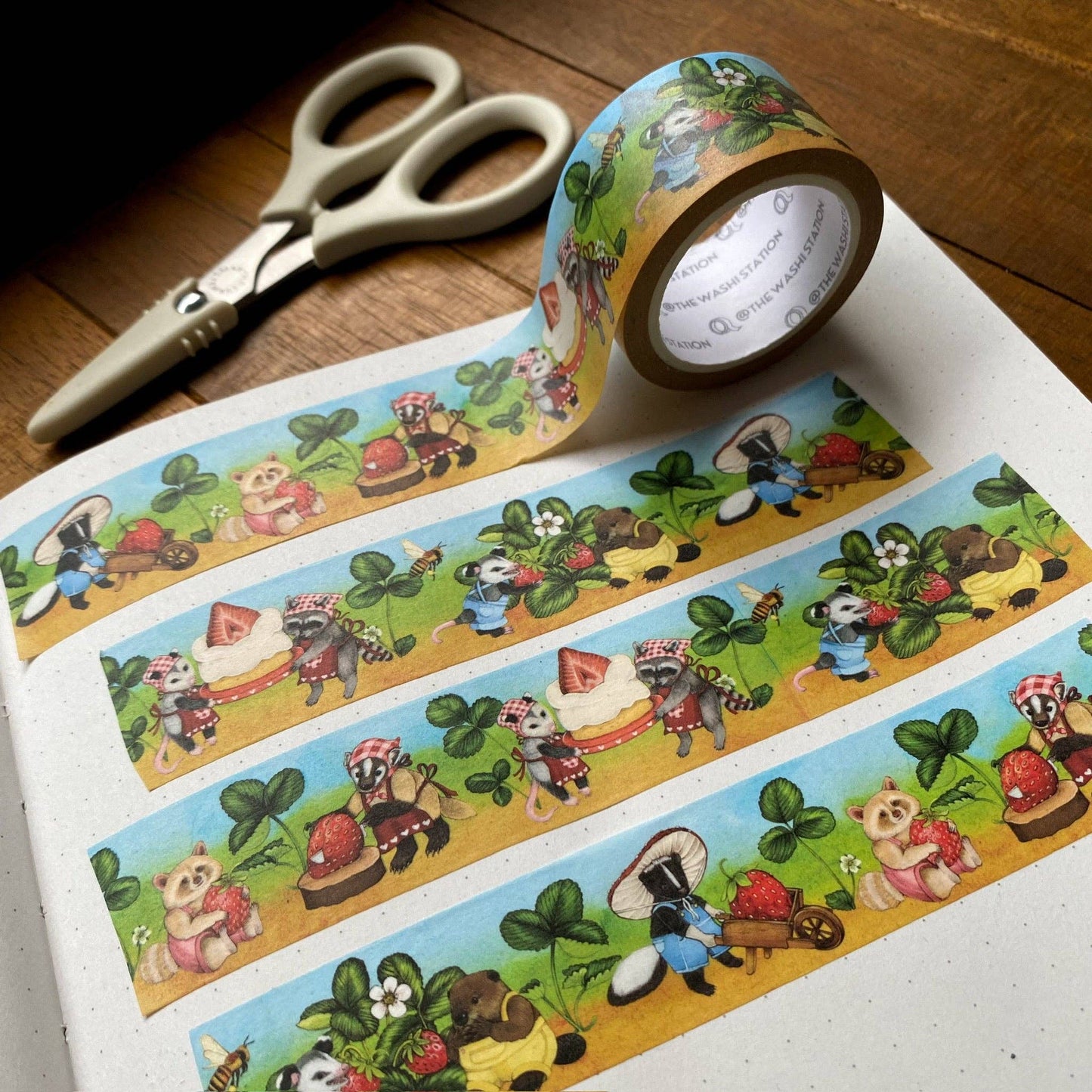 Decorative tape with cartoon raccoons and scissors on a wooden surface