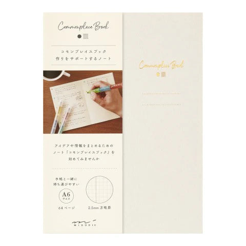 Notebook with a hand writing on a piece of paper, featuring the brand 'Commonplace Book'.