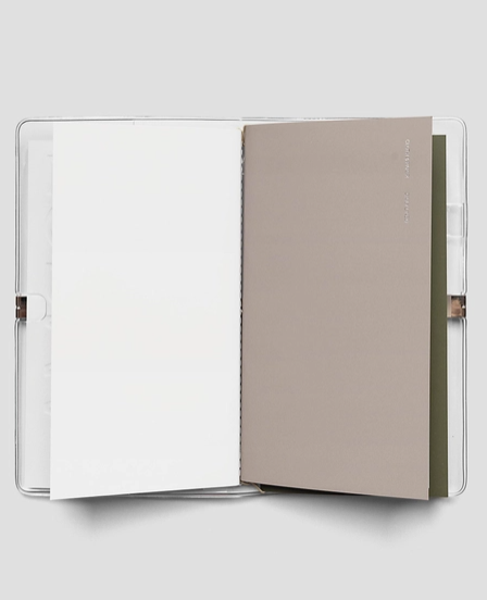 Open notebook with beige cover and white pages on a light gray background