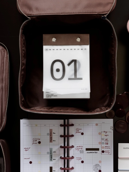 Calendar with '01' on a piece of paper inside an open suitcase.