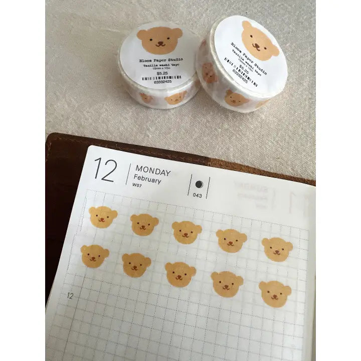 Two small containers of bear face stickers on a planner with bear face stickers applied.