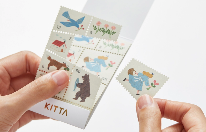 Hand holding a set of decorative stamps with cartoon characters on a white background
