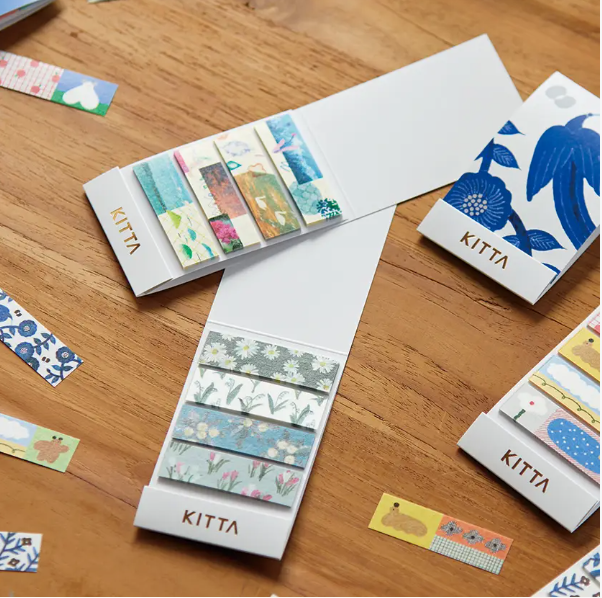 Kitta sticky notes with various designs on a wooden surface
