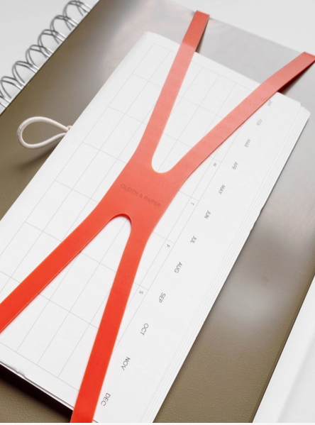 Notebook with a red ruler on top, placed on a light gray surface.