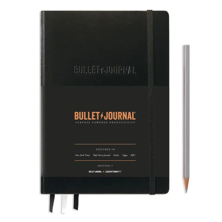 Black Bullet Journal notebook with a pencil on a white background