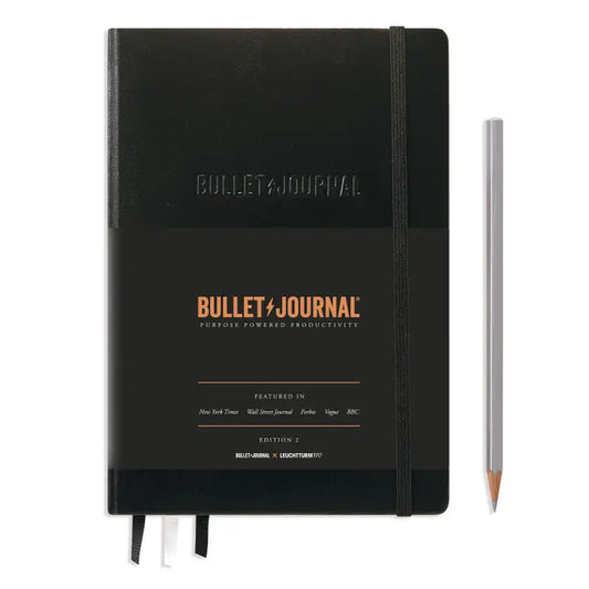 Black Bullet Journal notebook with a pencil on a white background
