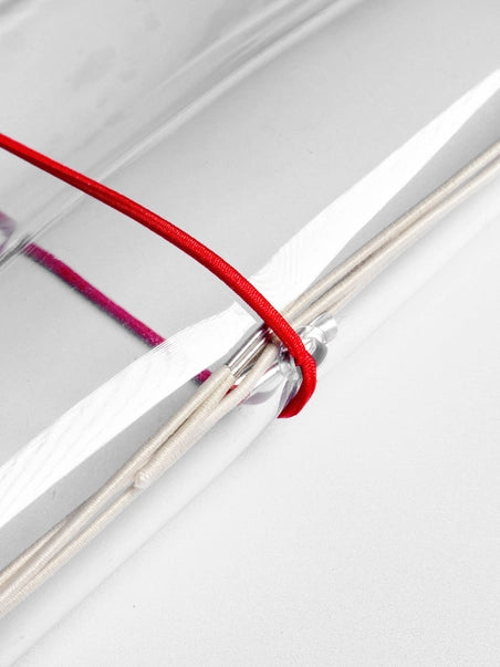 Close-up of a red thread tied to a clear plastic container on a white background