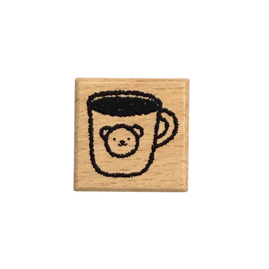 Wooden stamp with a design of a cup with a bear face on a white background