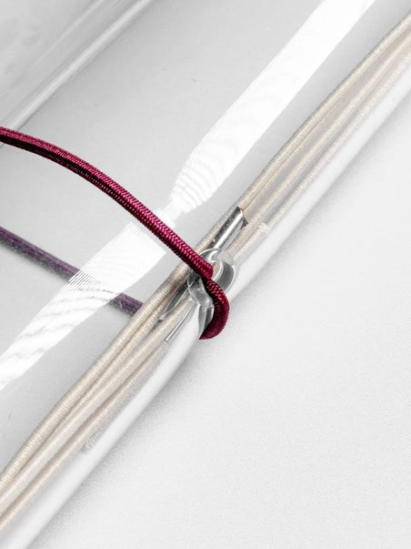 Close-up of a pink thread wrapped around a metal rod on a white background