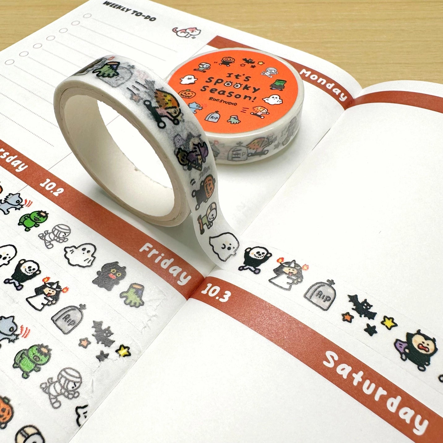 Halloween-themed washi tape on a planner with stickers.