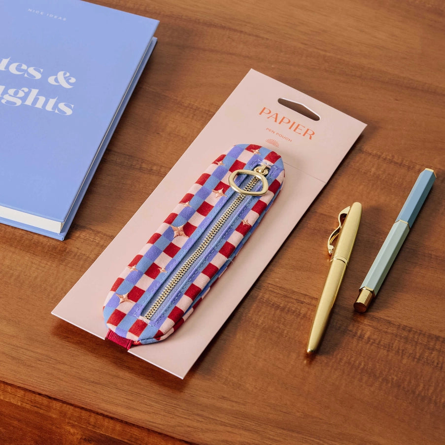 Papier checkered pouch with keychain, pen, and notebook on a wooden surface