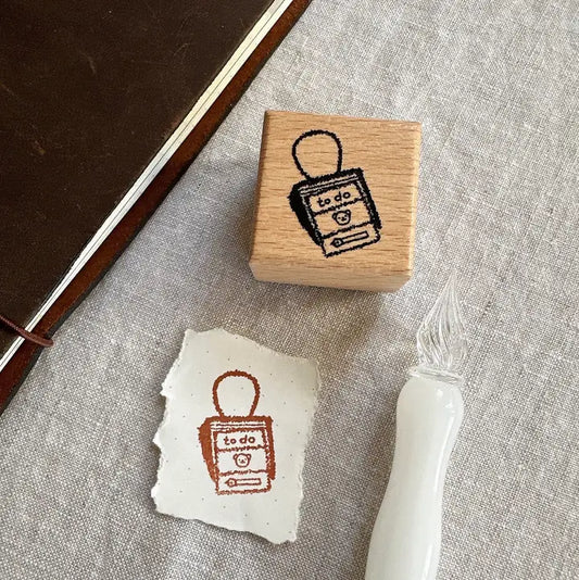 Rubber stamp with 'to do' list design on a piece of paper and a stamp pad.