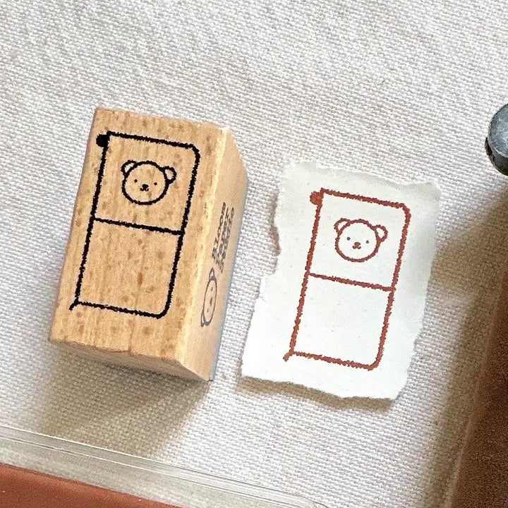Wooden stamp with a bear design and stamped paper on a textured surface
