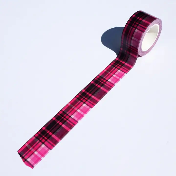 Roll of pink and black plaid tape on a light purple background