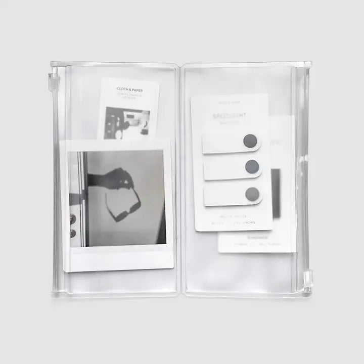 Clear plastic photo album with black and white photos on a light gray background
