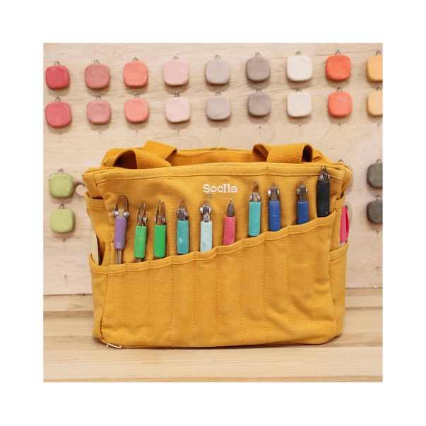 Yellow tool roll with colorful tools on a wooden background