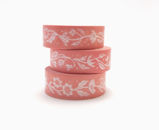 Three rolls of pink washi tape with white floral patterns on a white background