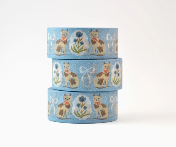 Three rolls of decorative tape with cat and flower designs on a blue background.