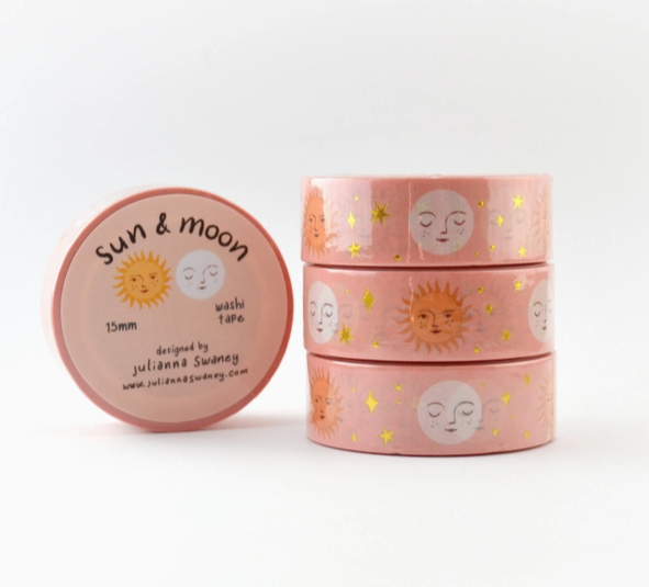Stack of pink washi tape rolls with sun and moon designs on a white background