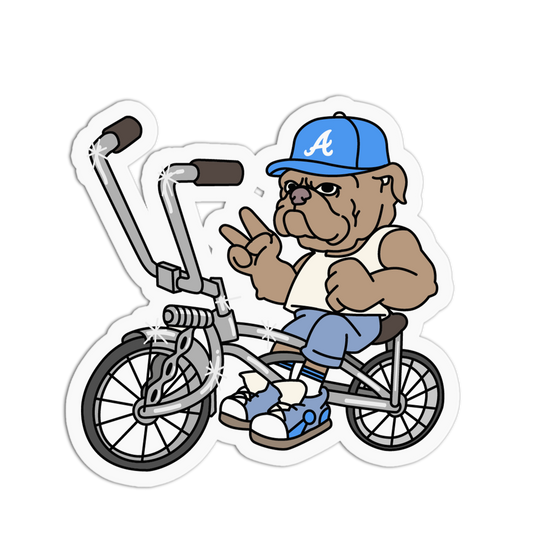 A die-cut sticker featuring a cartoon bulldog riding a BMX bicycle. The bulldog is wearing a blue baseball cap with a white 'A' logo, a white tank top, blue jeans, and blue sneakers, while making a peace sign.