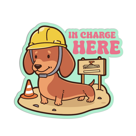 Sticker of a dog wearing a hard hat with 'In Charge Here' text on a white background