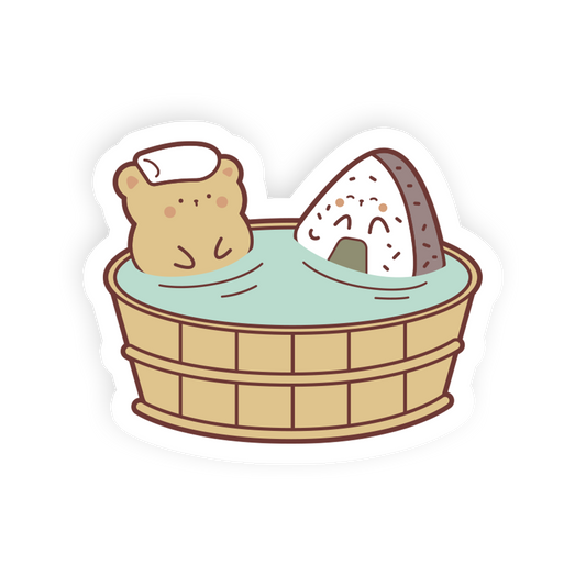 A cute cartoon die-cut sticker showing a small tan bear wearing a white headband sitting in a wooden bath tub with light blue water, alongside a triangular white rice ball with a brown crust.